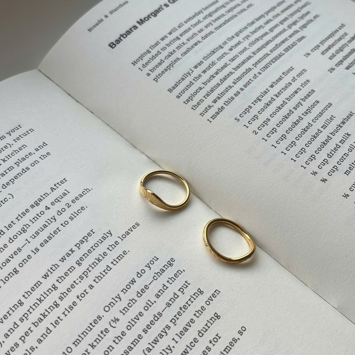 Two small gold hoop earrings resting on the pages of an open book with printed text.